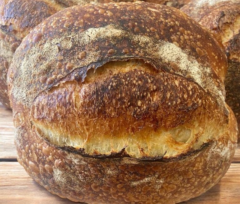 Picture of a traditional sourdough country loaf in front of other loaves